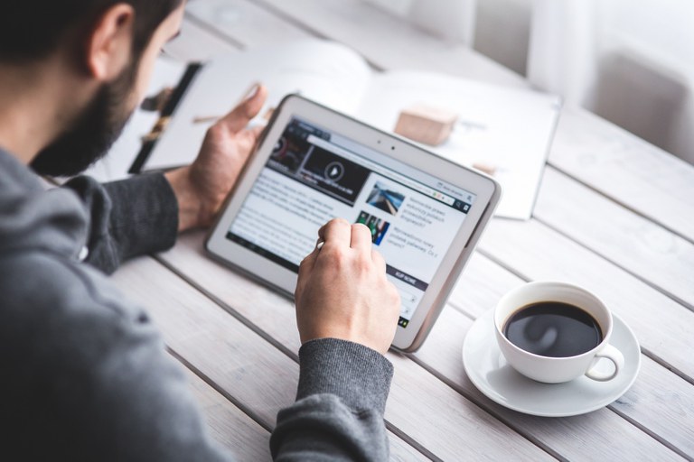 man-sitting-at-table-with-coffee-cup-using-digital-tablet.jpg